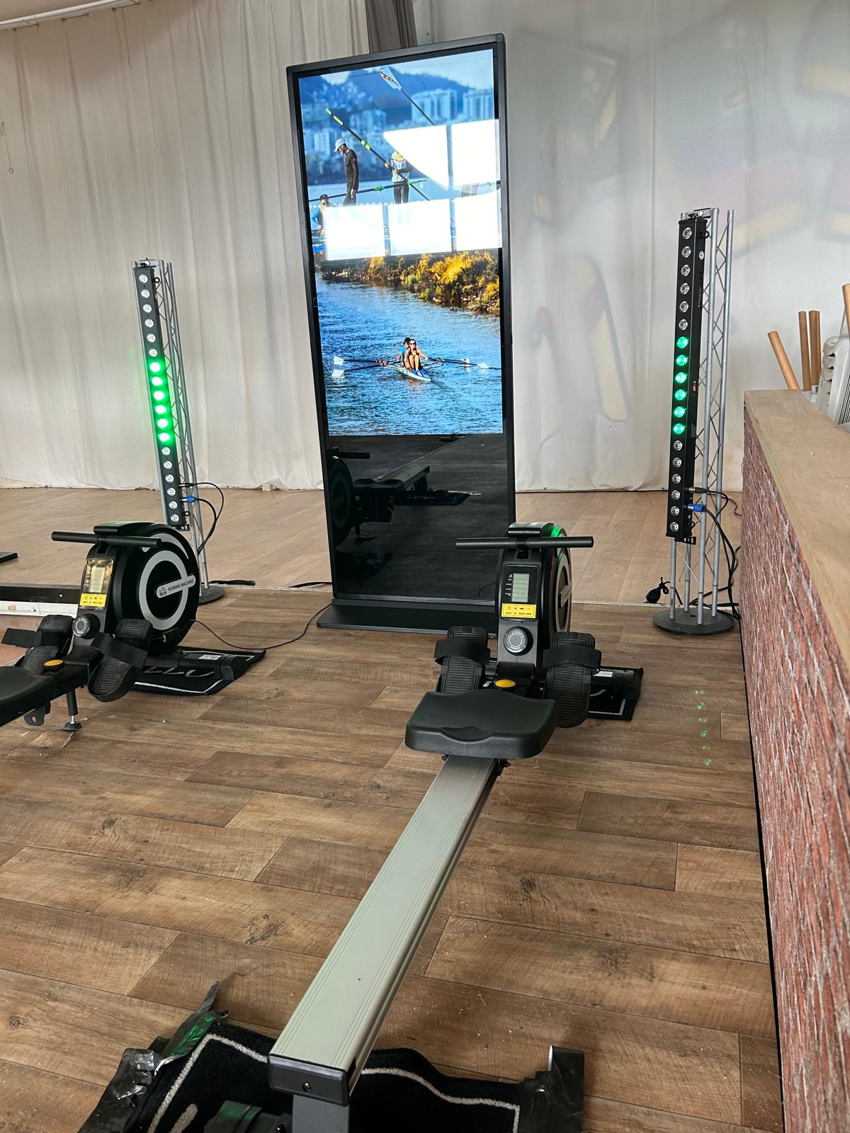 Deux ergomètres et un totem vidéo encadrés par des barres LED dans une salle de réception