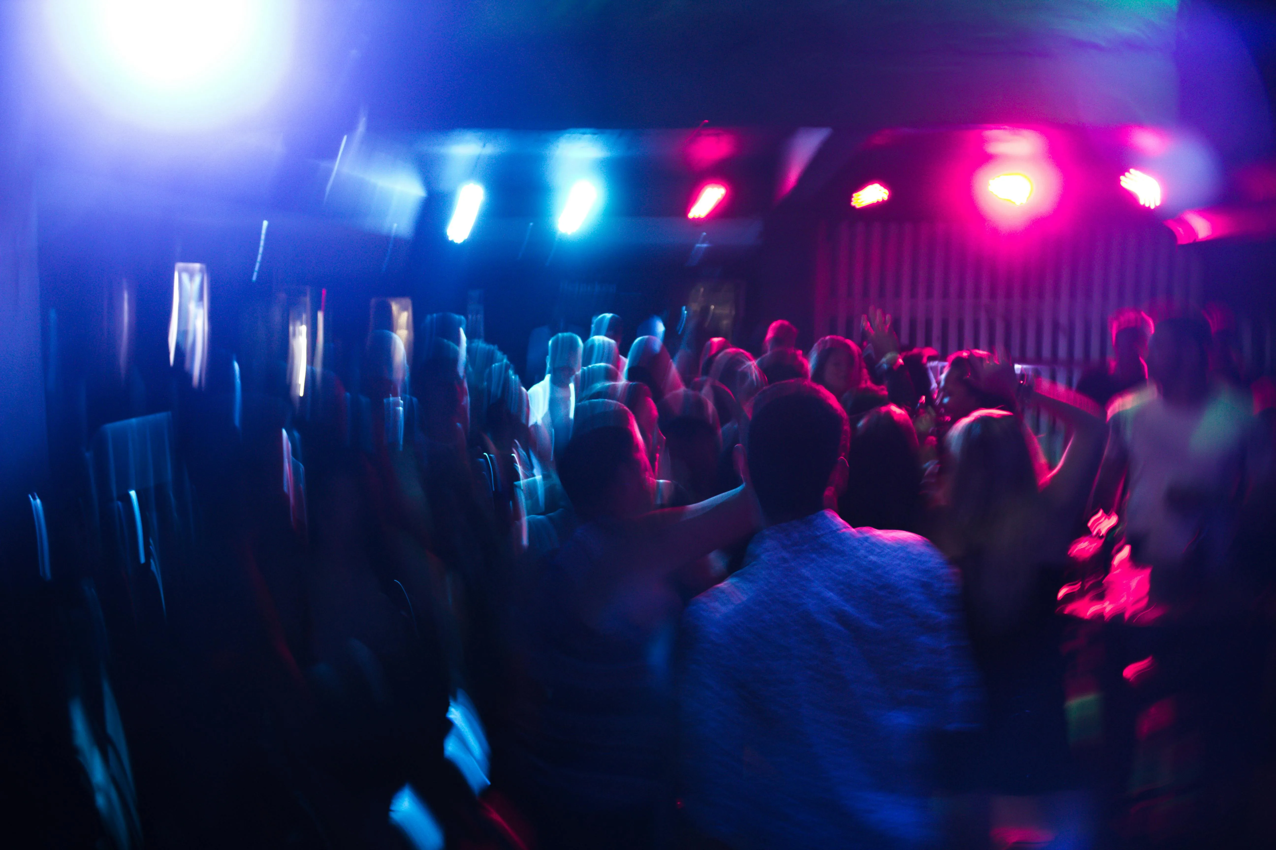 Foule en mouvement dans un bar sous des éclairages bleus et roses lors d'un afterwork